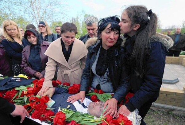 Elena Rybak, widow of Vladimir Rybak, at his open casket on the funeral on 24 April 2014. She is accompanied by her 13 y.o. daughter who comfort her mother at the father's casket.